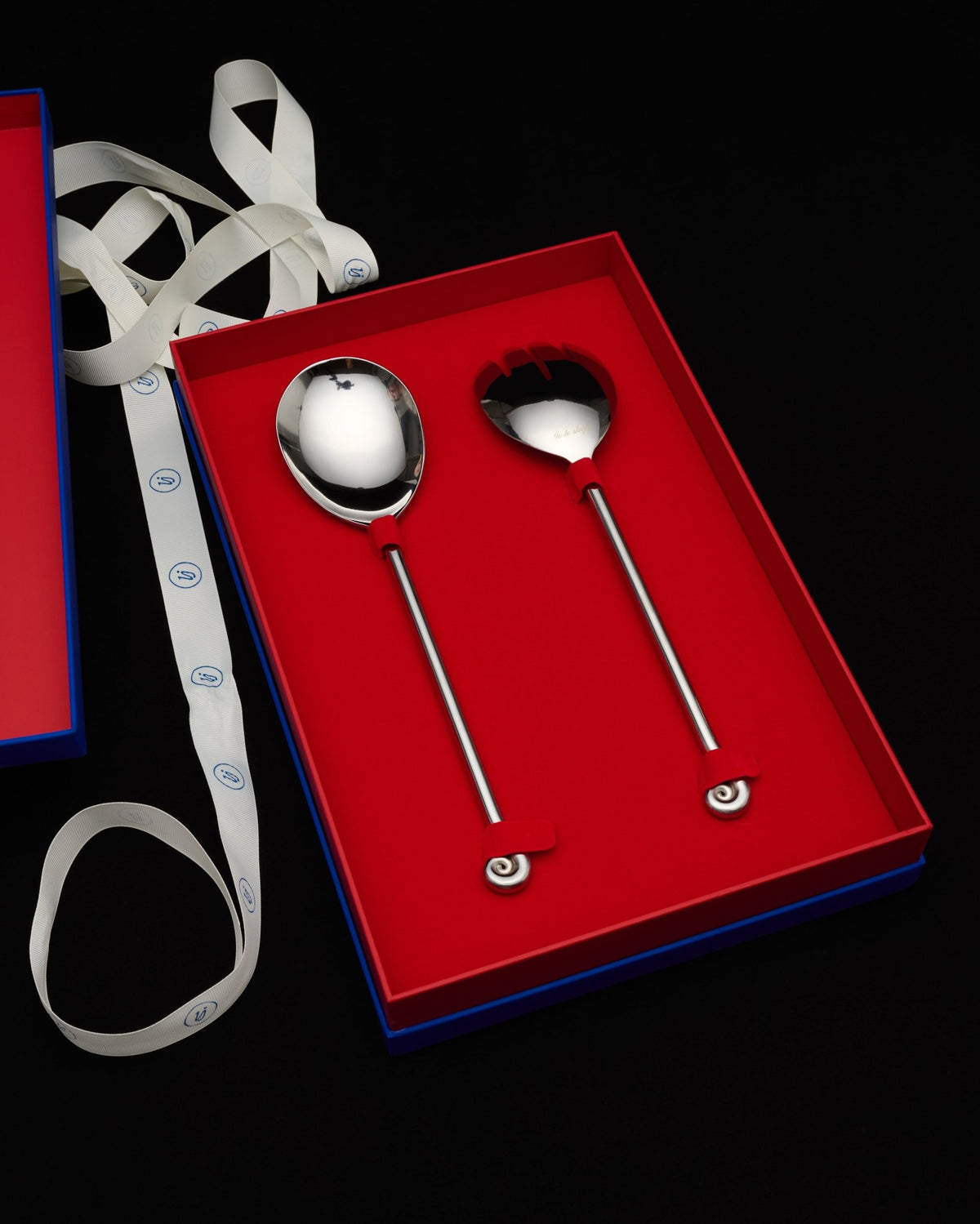 serving set in its open red gift box with a ribbon, on black