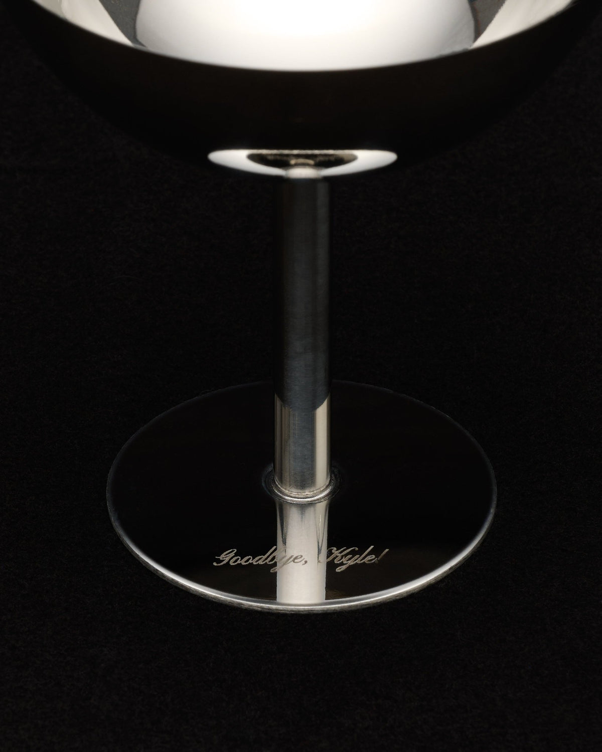 engraved base of a stainless steel coupe reading "goodbye, kyle!", on black